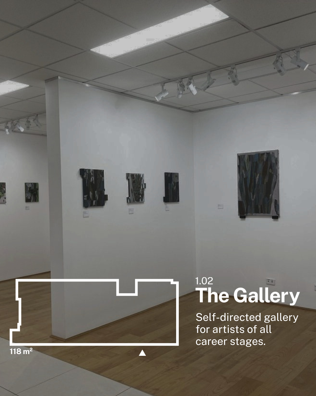 Interior of an art gallery with white walls, wood floors, and spotlights on the ceiling. Several abstract paintings are hung on the walls.