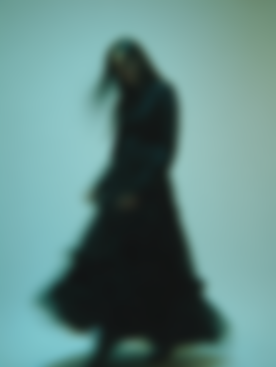 Blurred image of a woman in a long black dress standing against a gradient background.