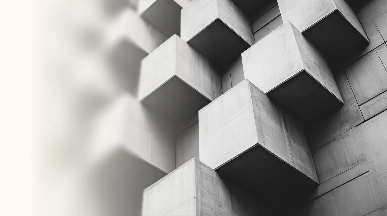 A black and white abstract image of concrete cubes with a gradient fade on the left.