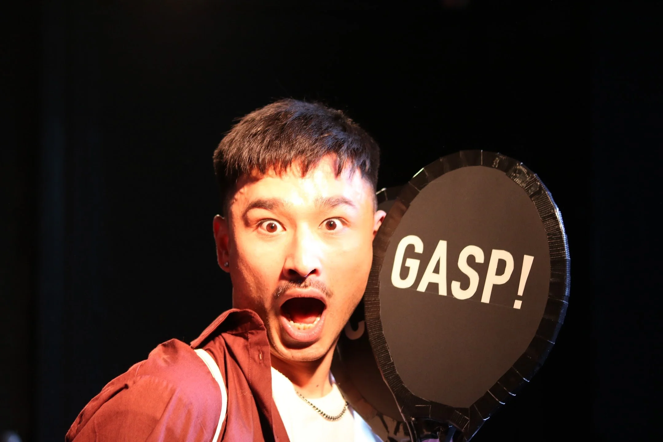 A surprised man holding a large black balloon with the word 'GASP!' written on it.