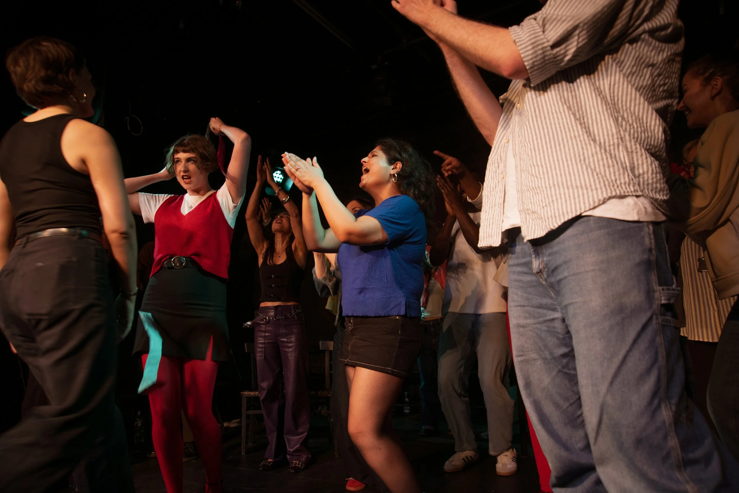 People dancing and enjoying themselves at a social event or party in a dimly lit space.