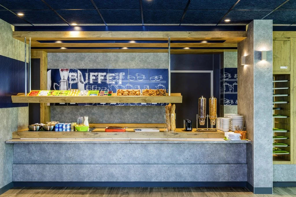 Angolo colazione con cereali, pane, marmellate e stoviglie in un bar o in un hotel.