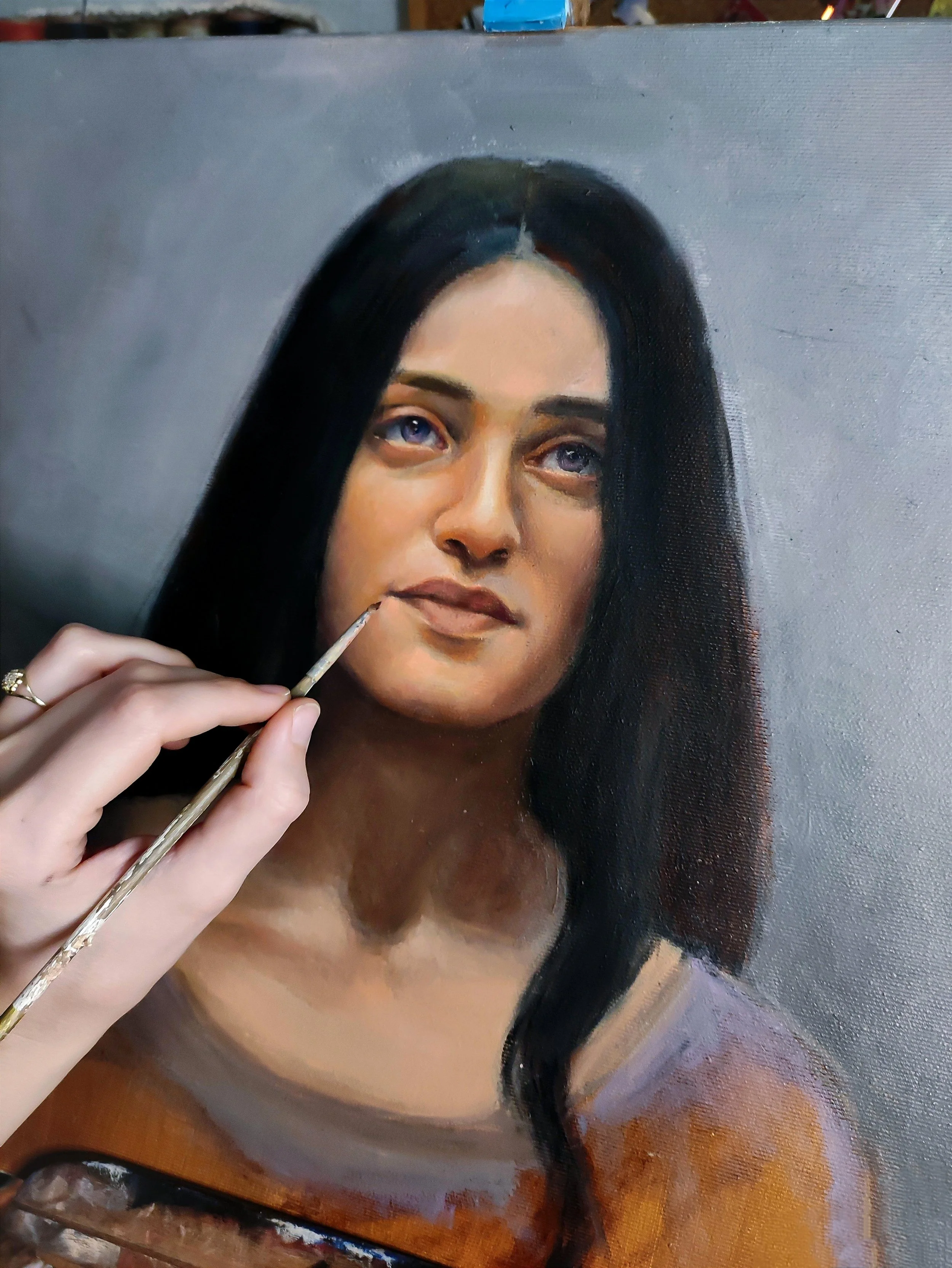 A person painting a realistic portrait of a woman with dark hair and light skin, focusing on the woman's face. The Woman is Yennefer from the Witcher series