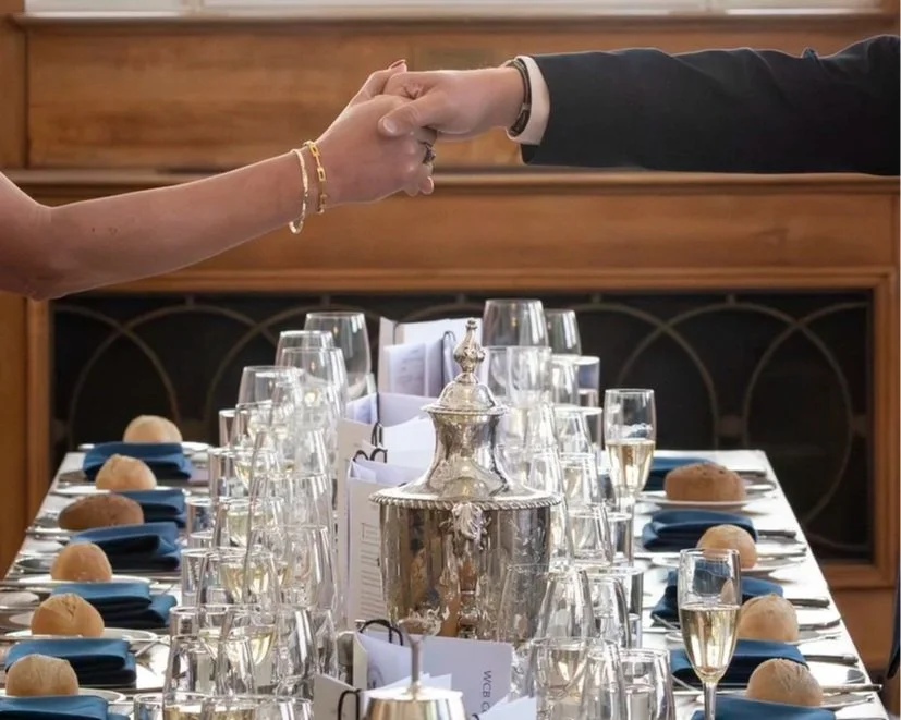 man+and+woman+shaking+hands+over+long+table+corporate+lunch+apr+2026.jpg