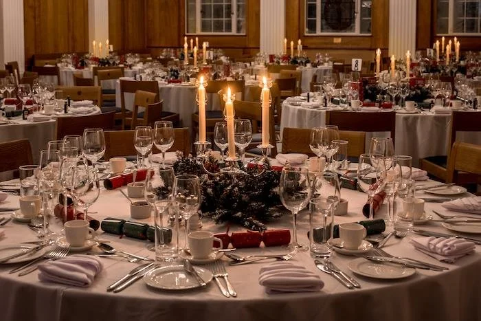 Wedding reception table decorated with candles, winter-themed decorations, and neatly arranged tableware in a wooden banquet hall.