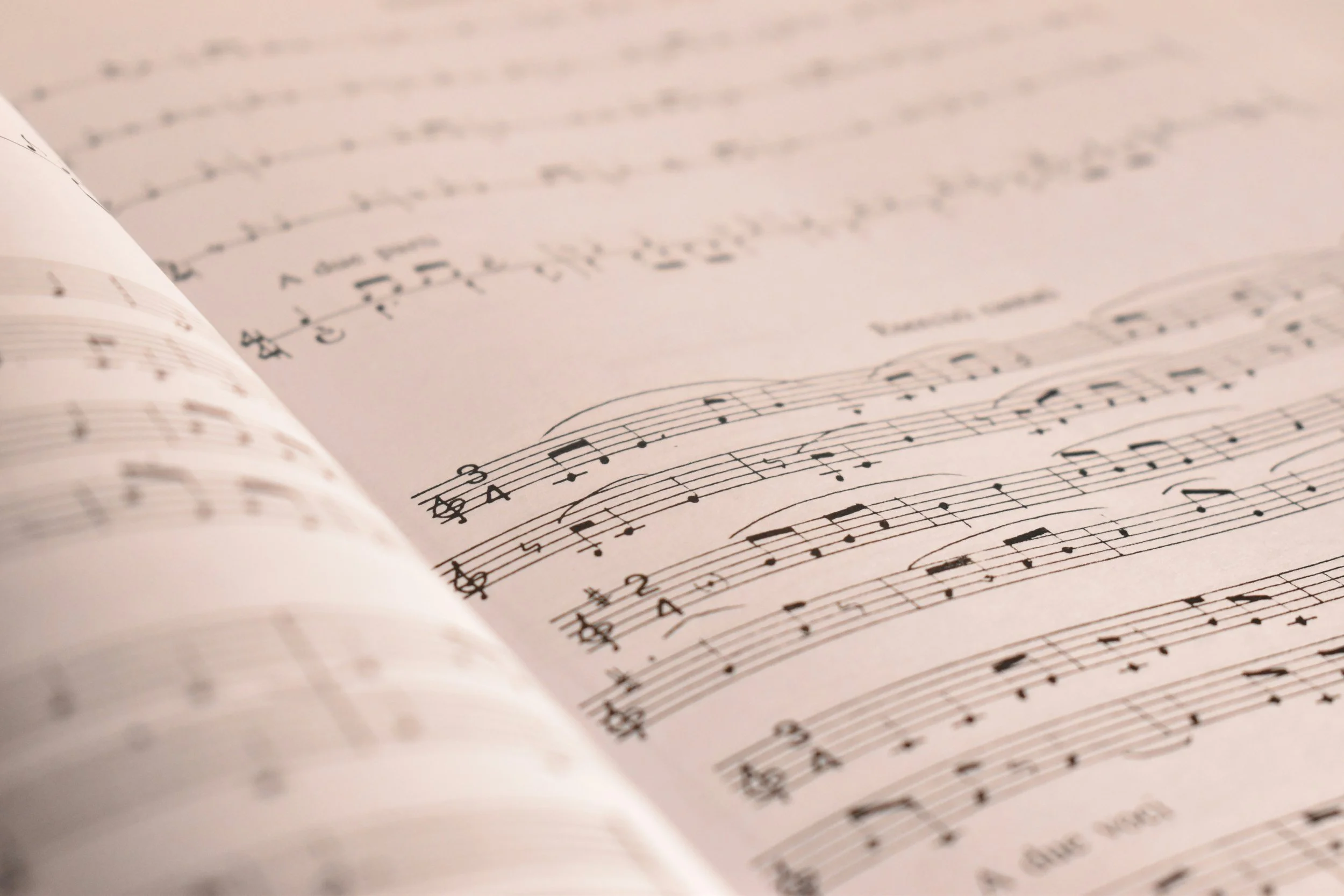 Open sheet music with musical notes and staff lines, slightly curled at the edges.
