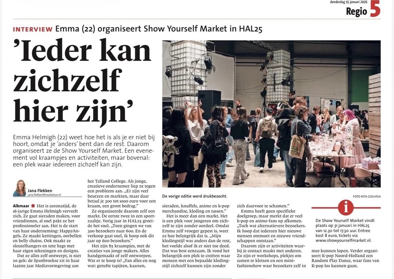 Binnen een grote hal is er een evenement met veel mensen. Er zijn stellingen en tables met spullen, en er hangen lampen en speakers.