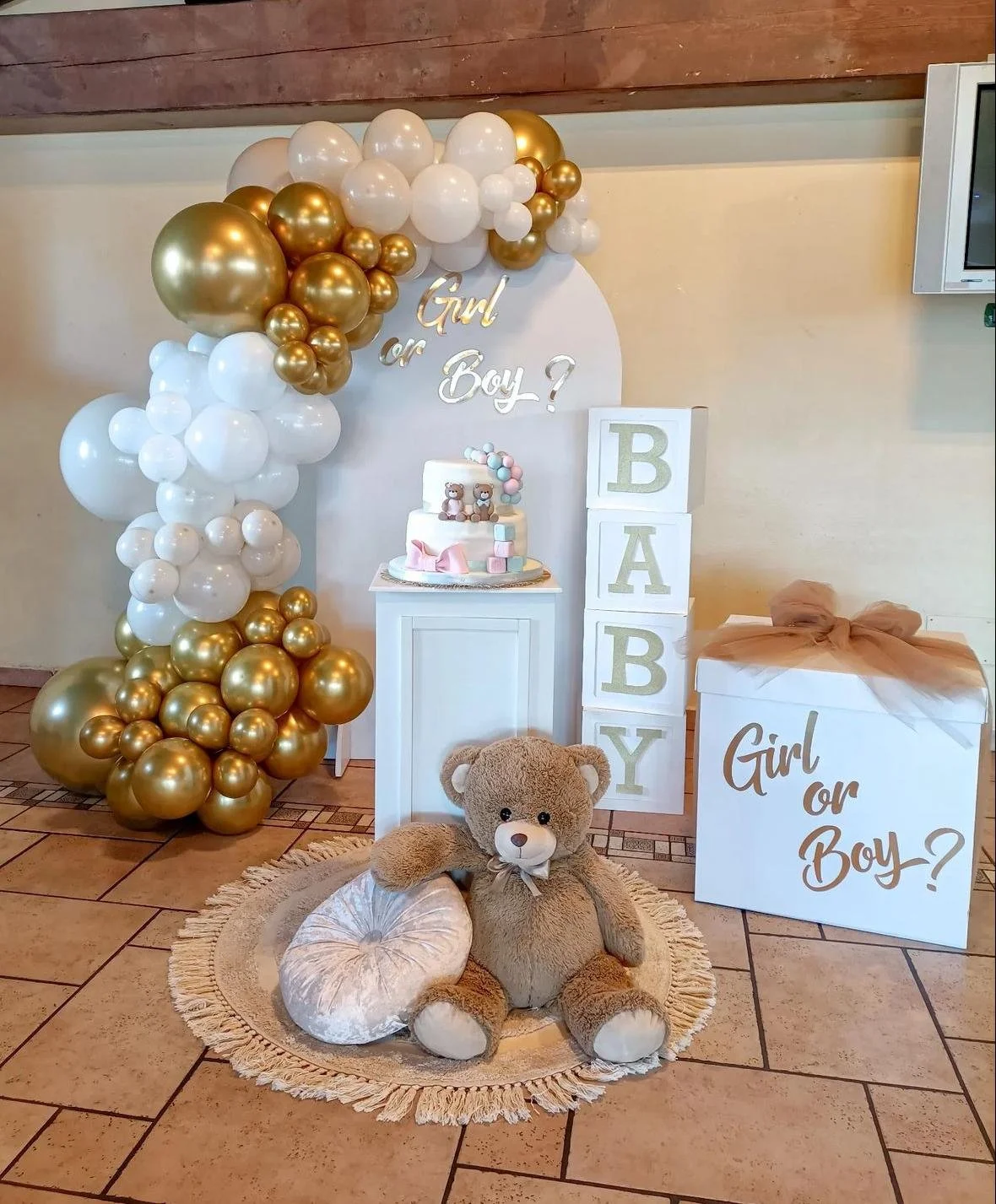 Decorazione per nascita con palloncini bianchi e dorati, teddy bear, torta e scatole con scritto Girl or Boy?.