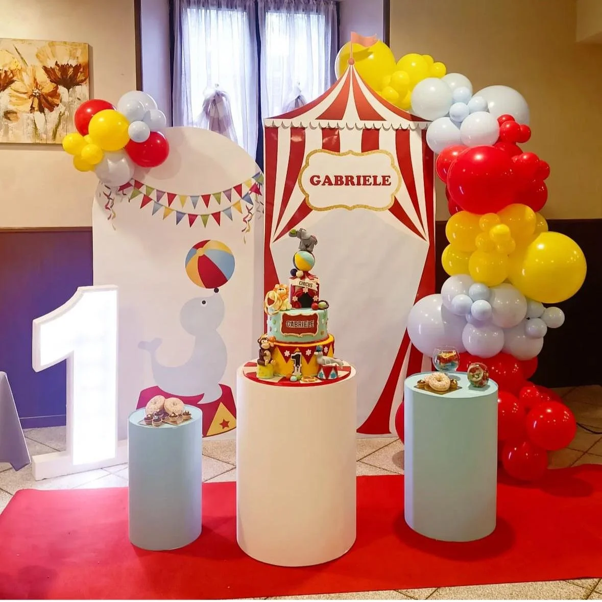 Decorazioni per festa di compleanno con tema circo e clowns, torta decorata e palloncini di colori rosso, giallo e bianco. Personalizzato con il nome Gabriele.