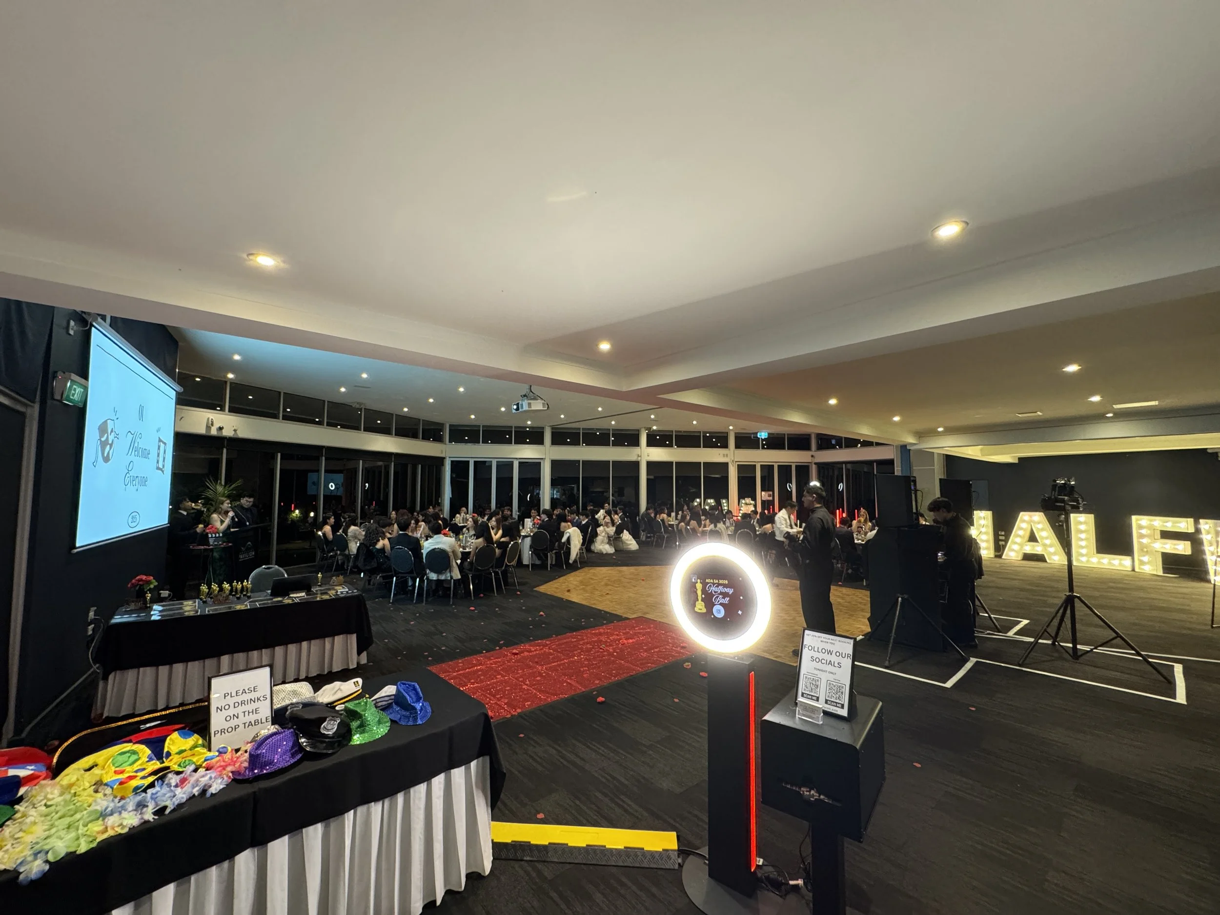 A large indoor event space with many round tables and chairs filled with people