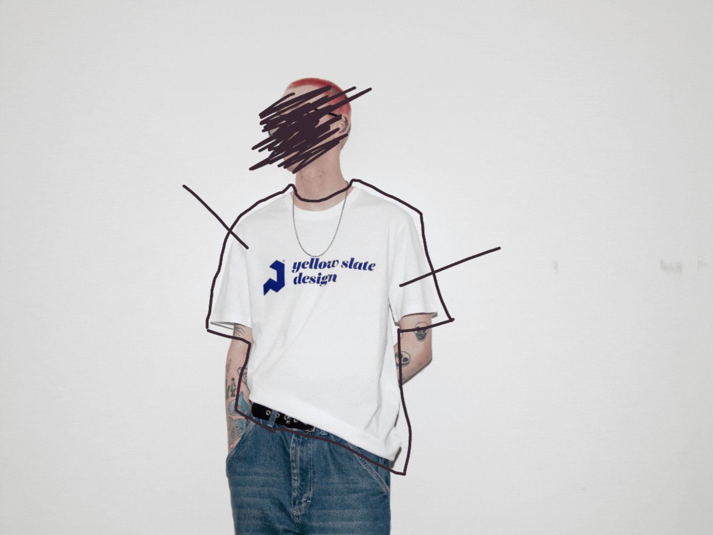 Person with styled hair and tattoos, wearing a white t-shirt with 'yellow slate design' logo, blue jeans, and a necklace, standing against a plain white background.