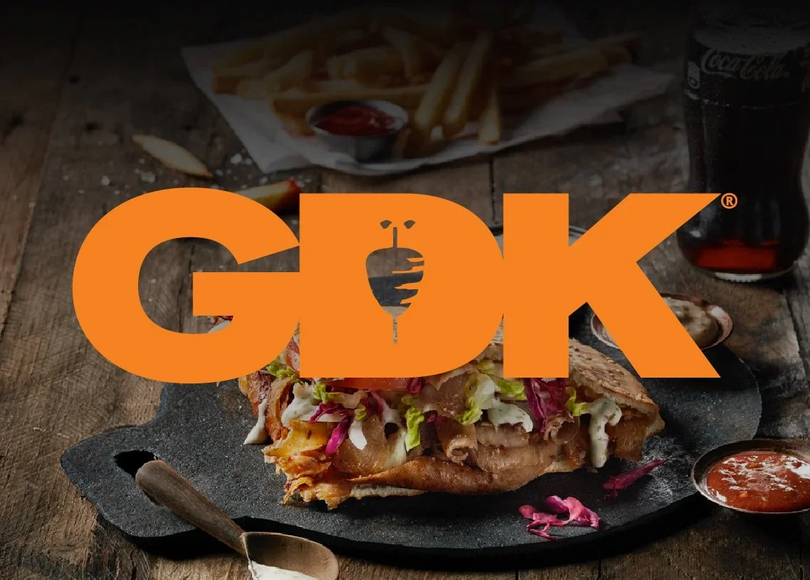 GDK logo overlays a picture of a plated kebab with salad and dipping sauces, with fries and a drink in the background.