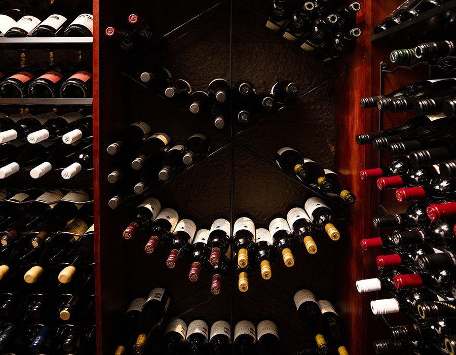 A wine storage closet with shelves filled with bottles of wine, organized by type and label.
