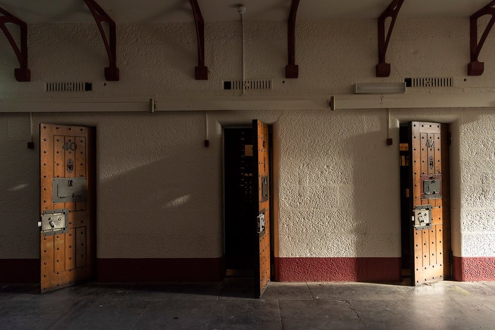 Three old wooden lockers with metal locks in a dimly lit hallway.