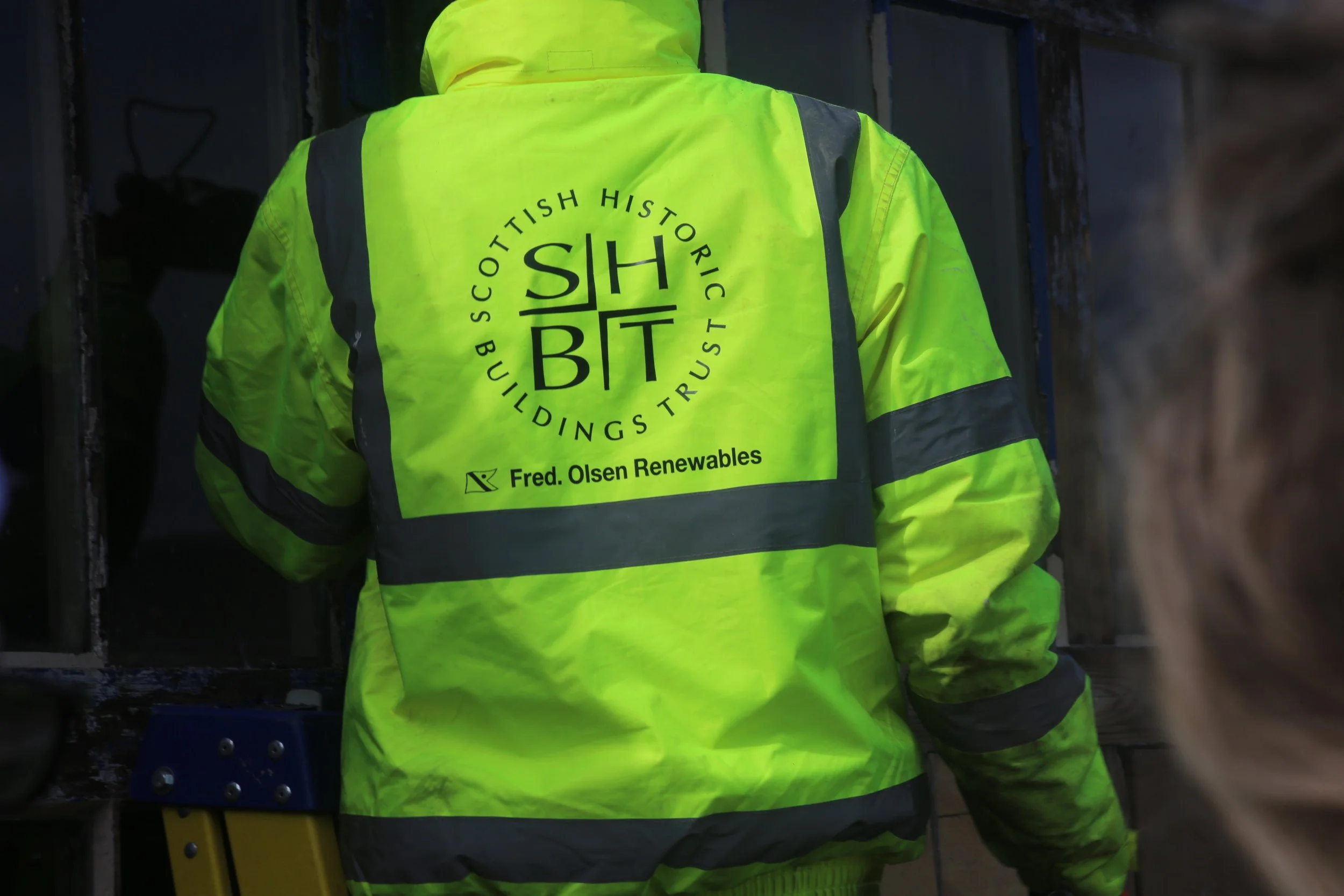 person wearing hi-viz jacket taken from behind, featuring Fred Olsen and SHBT logos