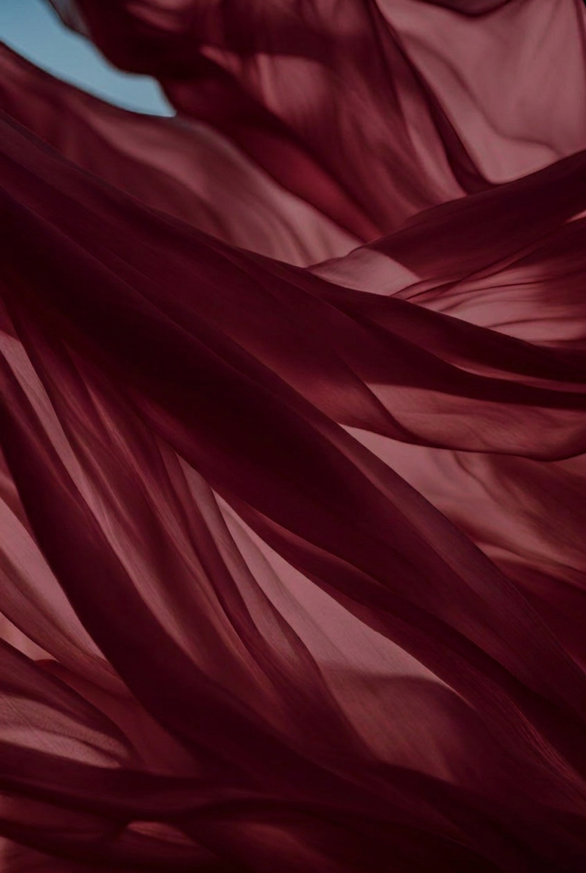 Close-up of flowing, layered red and pink fabric with soft lighting.