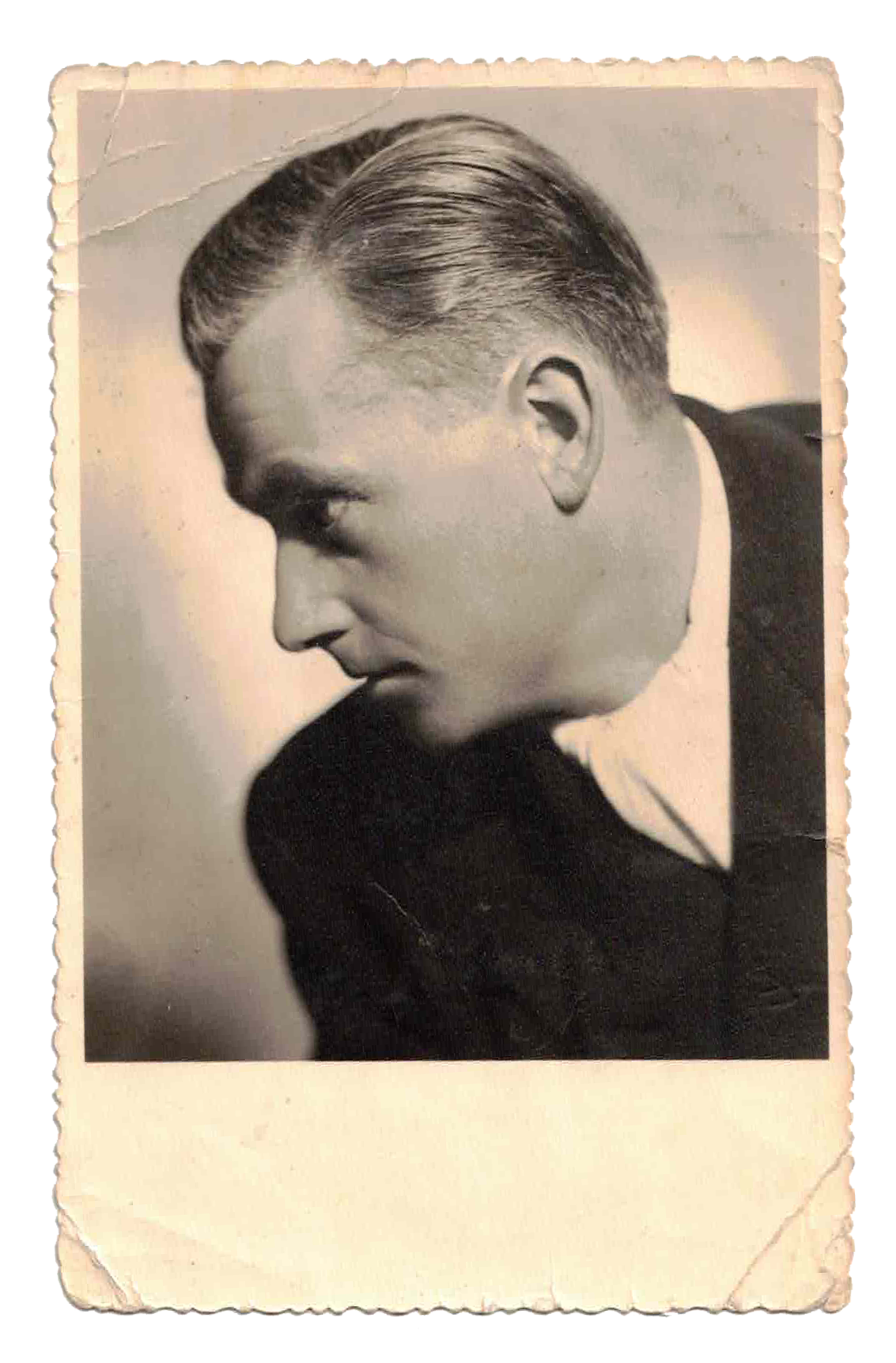Black and white vintage photo of a young man with a neatly combed hairstyle, dressed in a tuxedo, looking down and to the side.