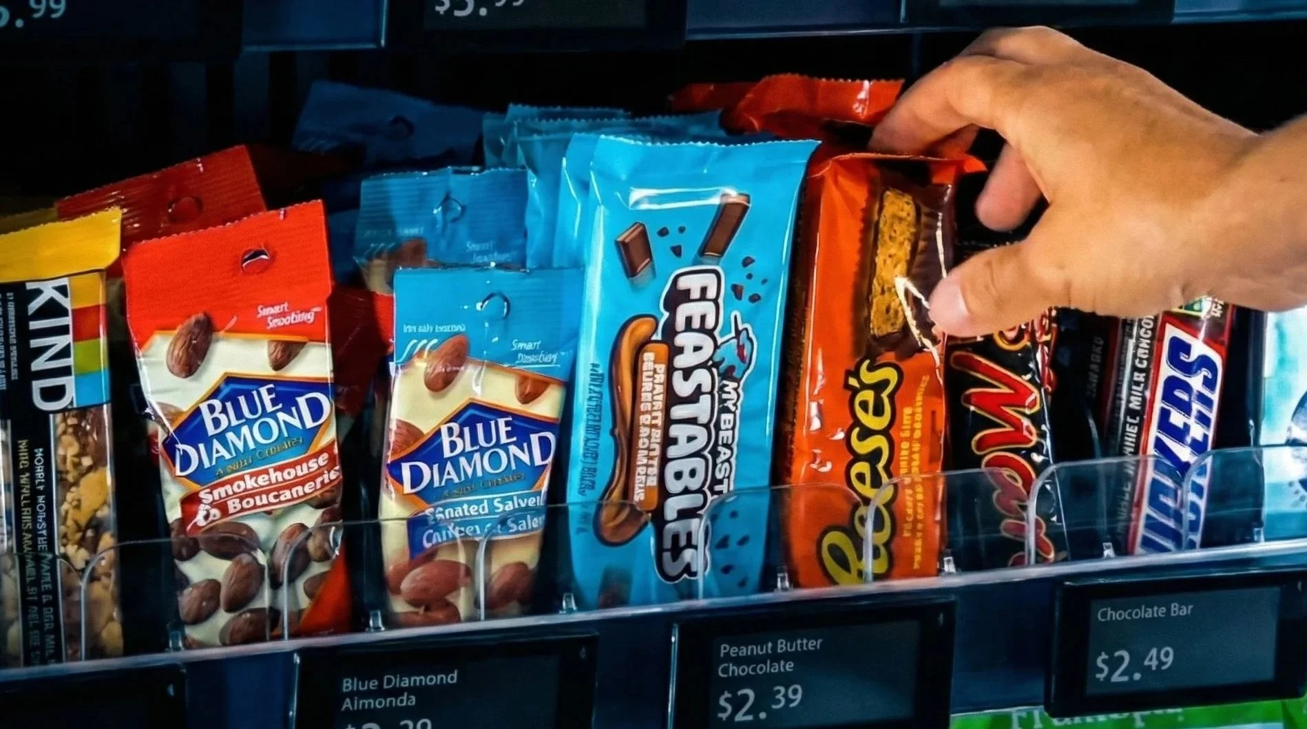 Store shelf displaying various snack chocolate bars, including Blue Diamond Almonds, Reese's, Snickers, and Kit Kat.