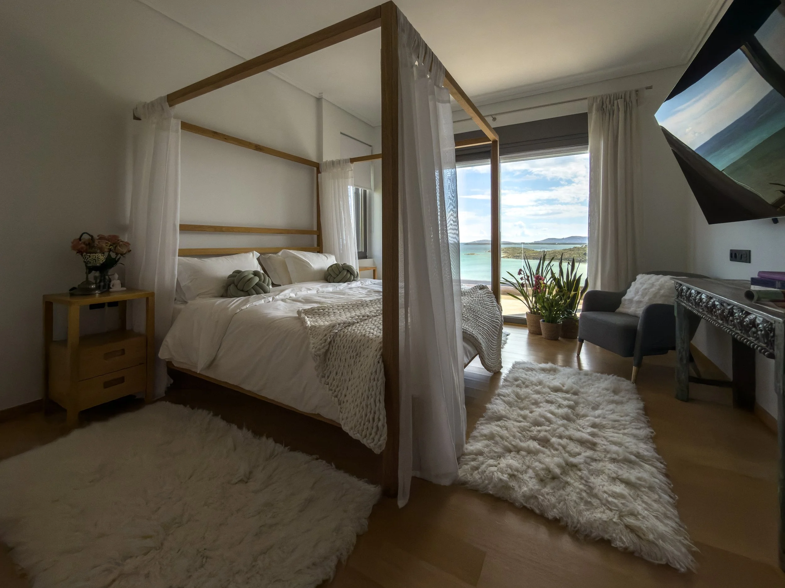 Restful bedroom retreat with layered textures and panoramic coastal views at Astraea Villa.