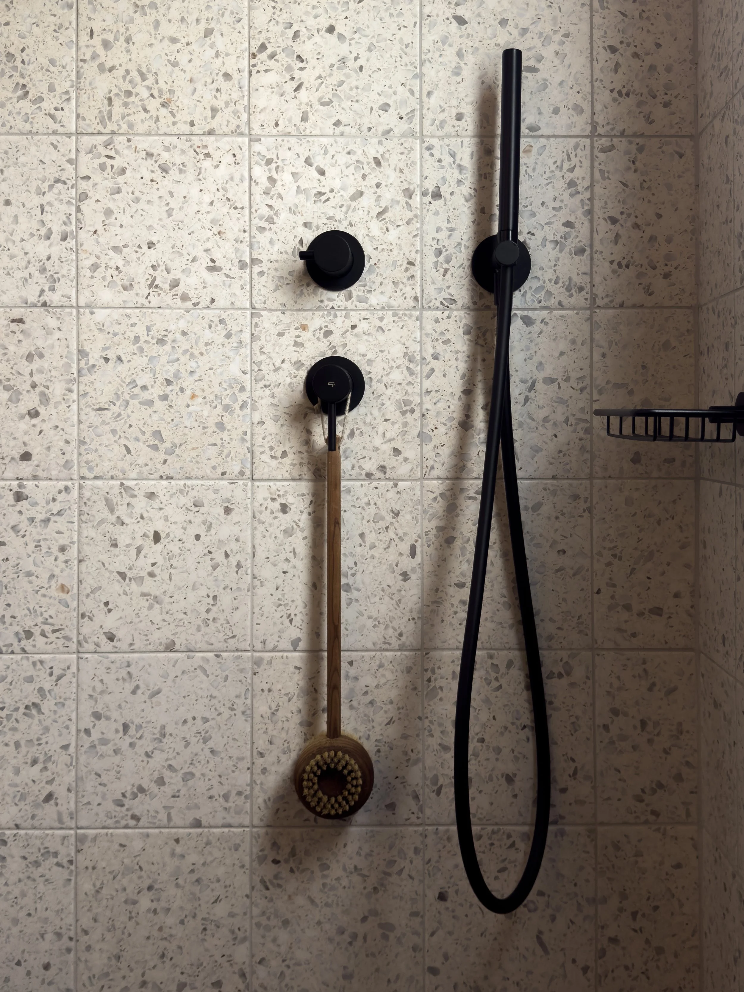 Matte black shower fixtures and tactile natural details at Astraea Villa.
