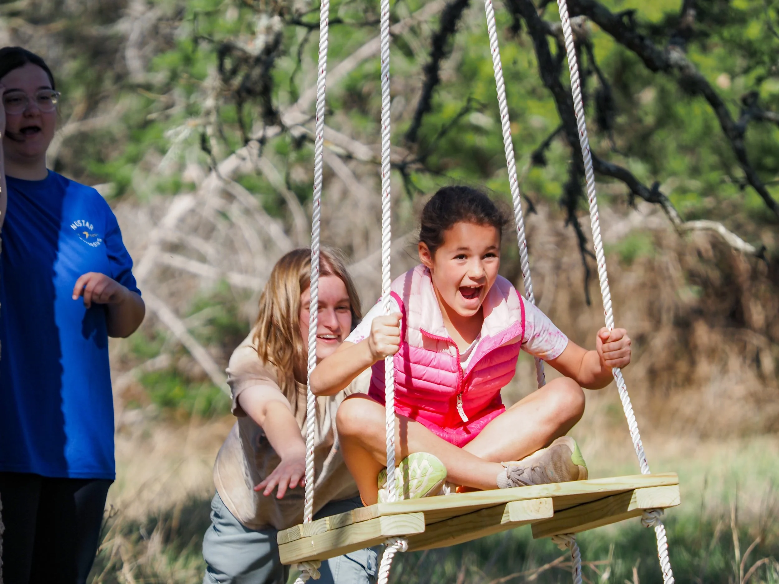 Counselor pushing a camper on a swing
