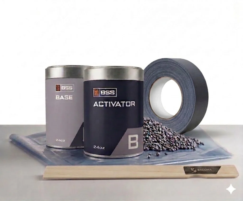Two cans labeled 'Base' and 'Activator' with a roll of black tape, scattered small black beads, a wooden spatula with 'Bacoma' branding, and a plastic sheet on a white surface.