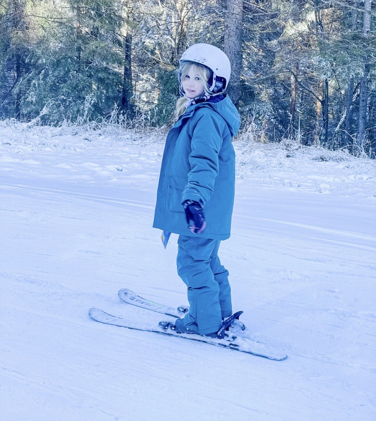 Young girl, skiing, in a dark green ski suit, and helmet on