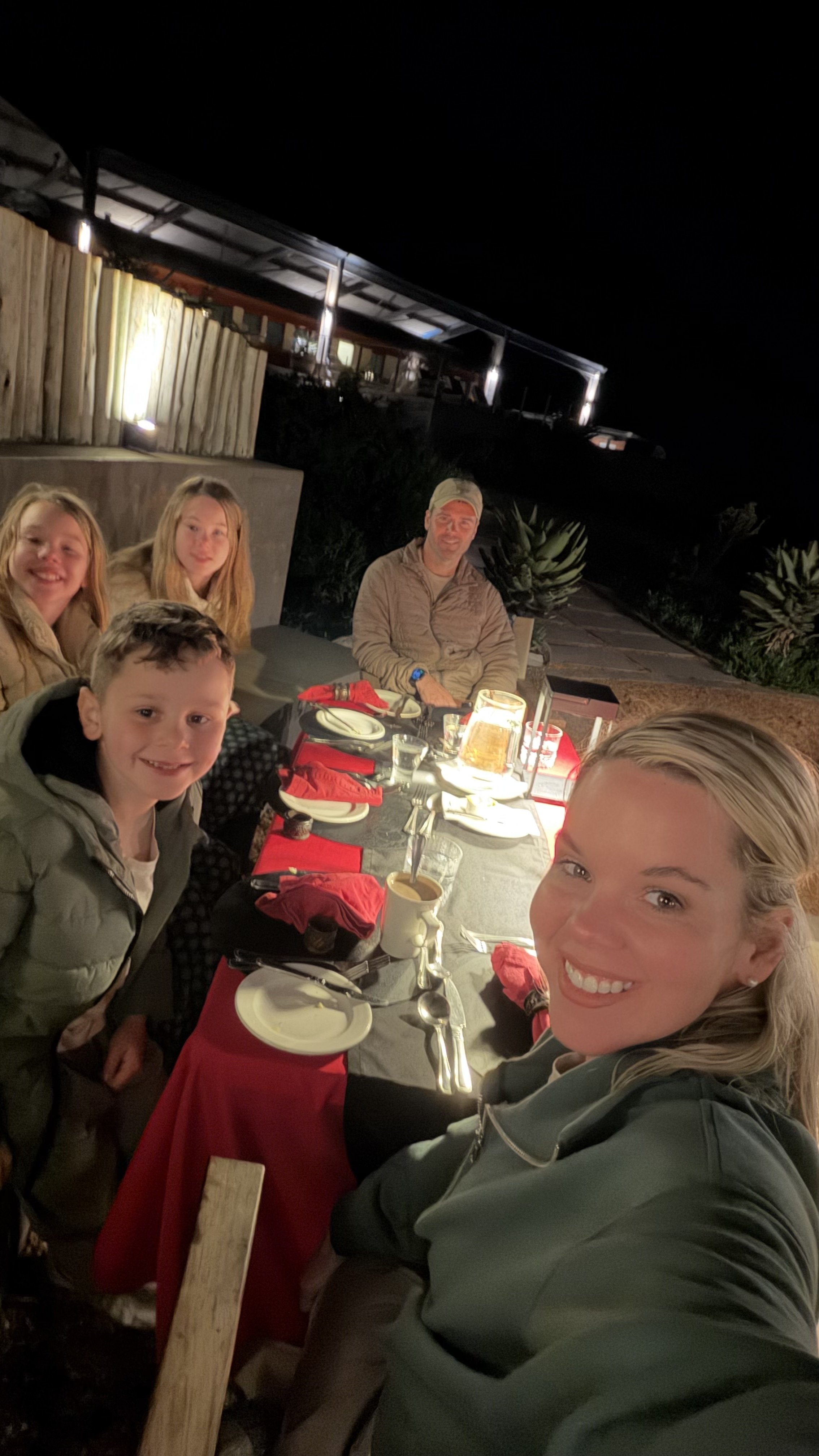 Boma Braai dinner outside of the safari lodge with family around the dinner table at night