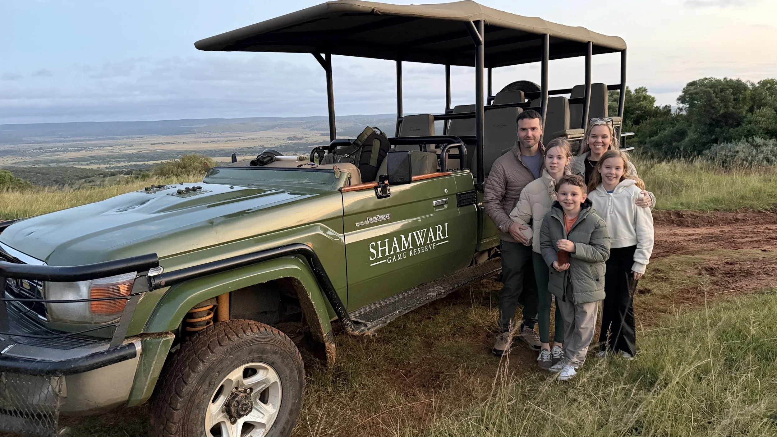 Shamwari Private Game Reserve jeep with a family of 5 standing in front of it one morning during a morning game drive in South Africa