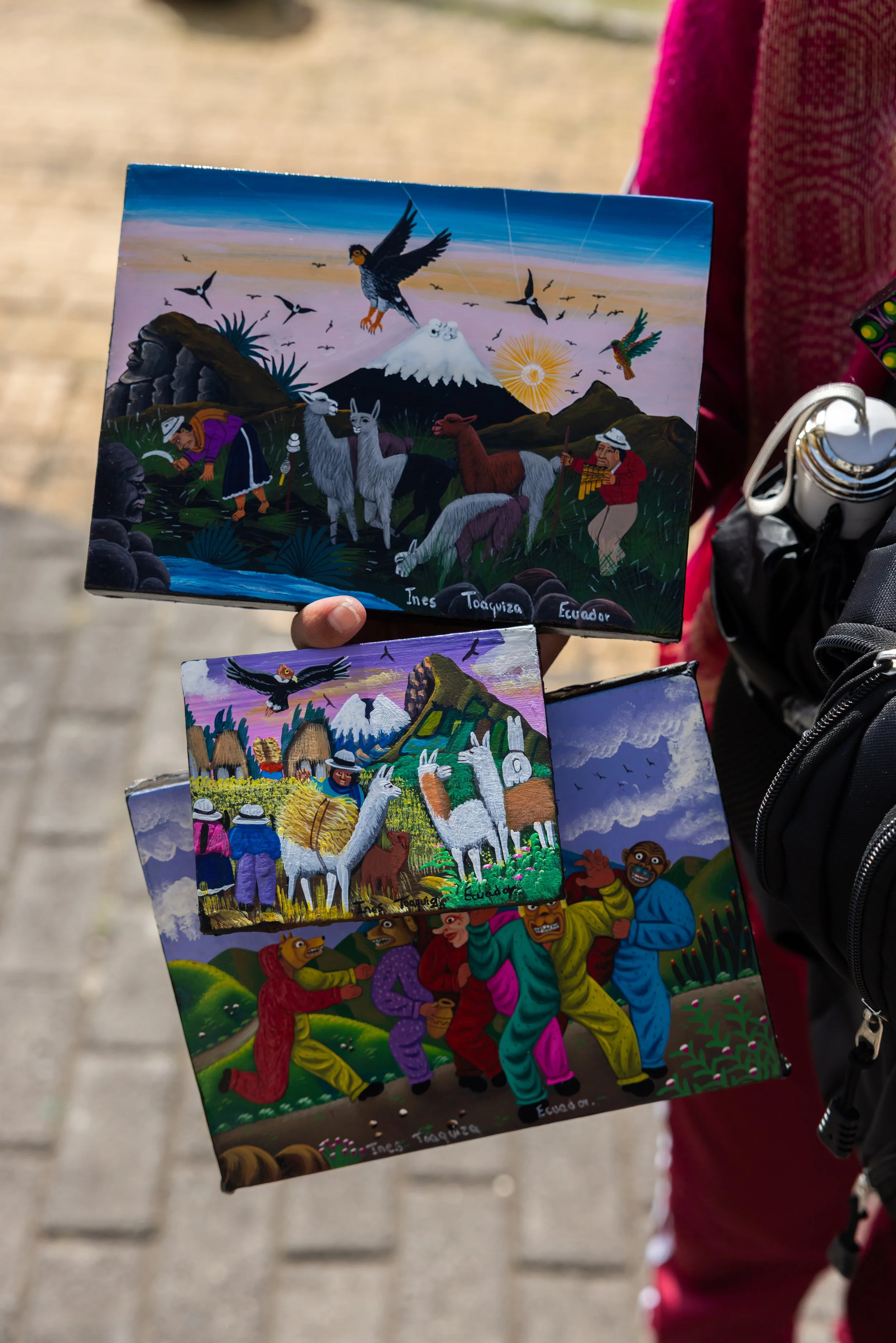 Colorful painting of Ecuadorian cultural scene with indigenous people, llamas, mountains, and birds, signed by Ines Tocuyuz