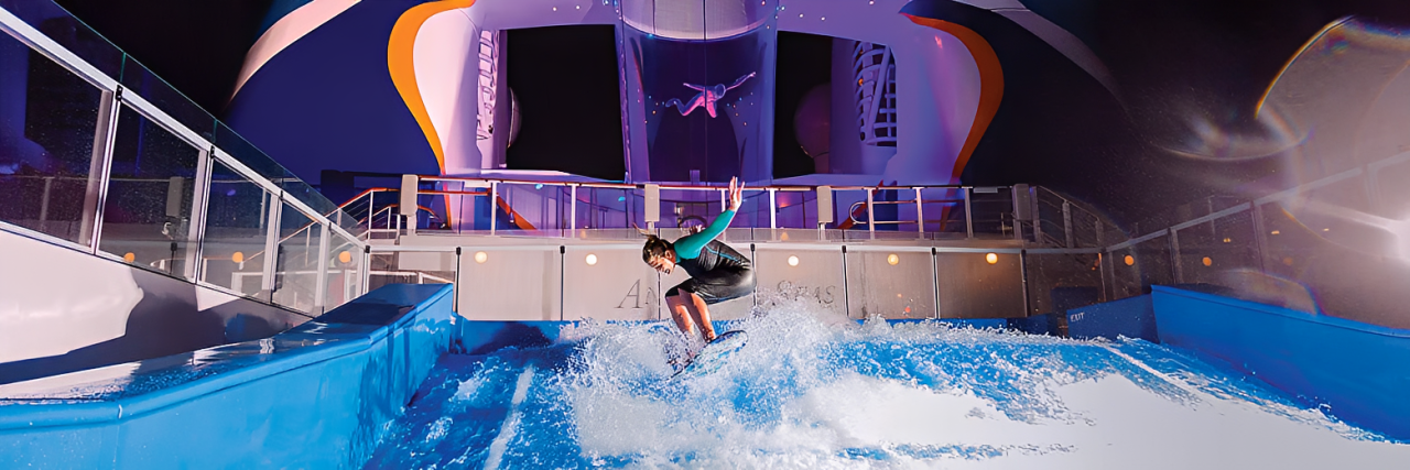 Person surfing on an indoor wave pool at an amusement park.