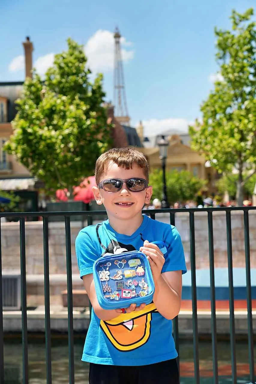 Young Boy, Donald Duck Shirt, Sunglasses, at Epcot, holding a Go Pin Pro pin holder with Disney Pins in it 