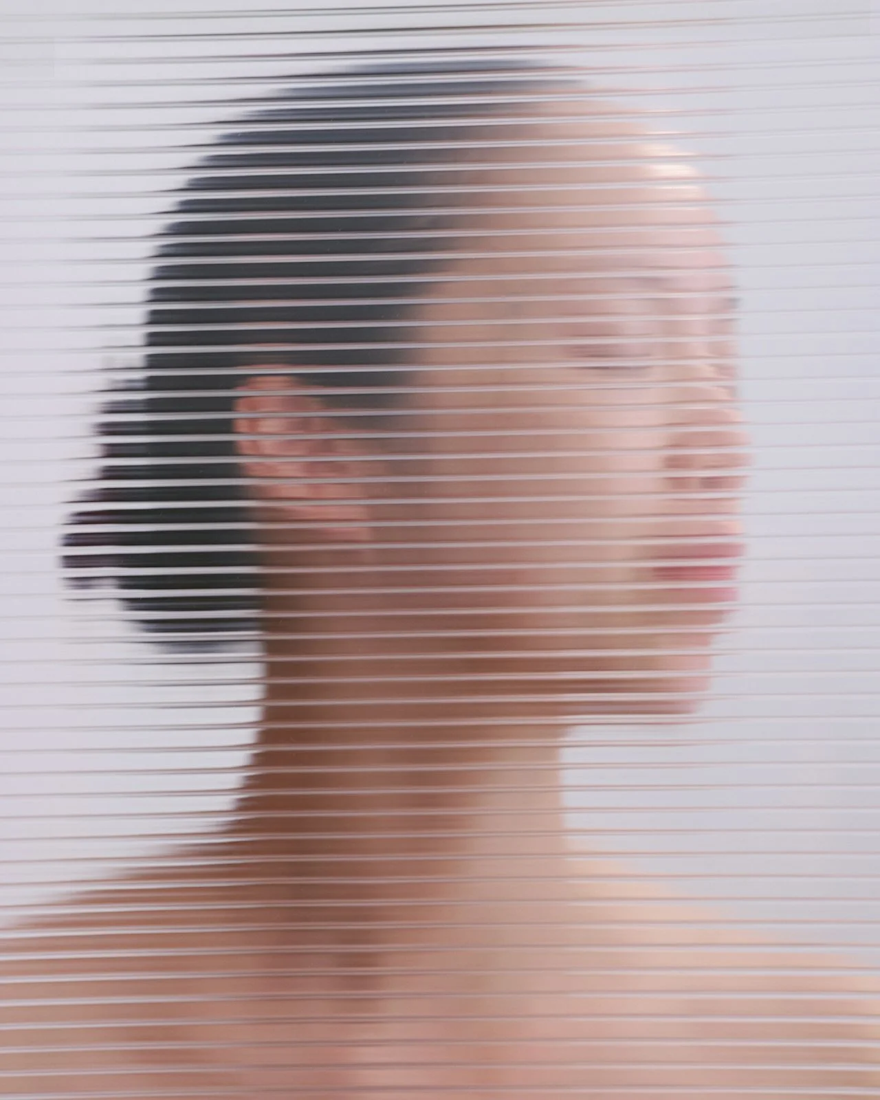 Person with dark hair and glasses seen through a frosted glass door.