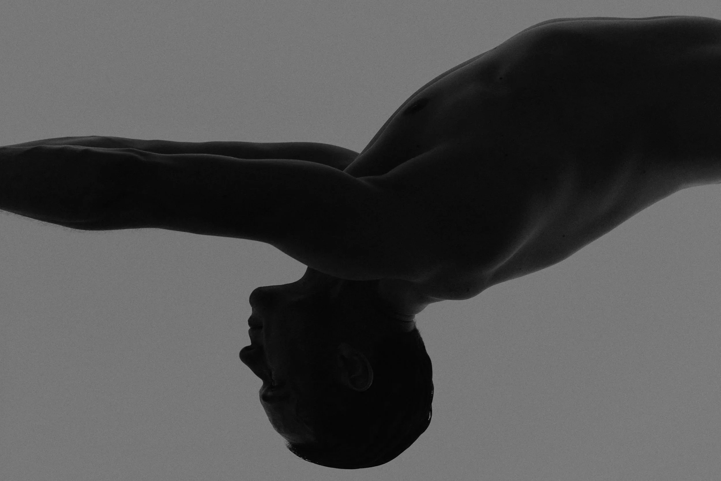 Silhouette of a person's face in profile with their hand resting on top of their head, seen against a plain background.