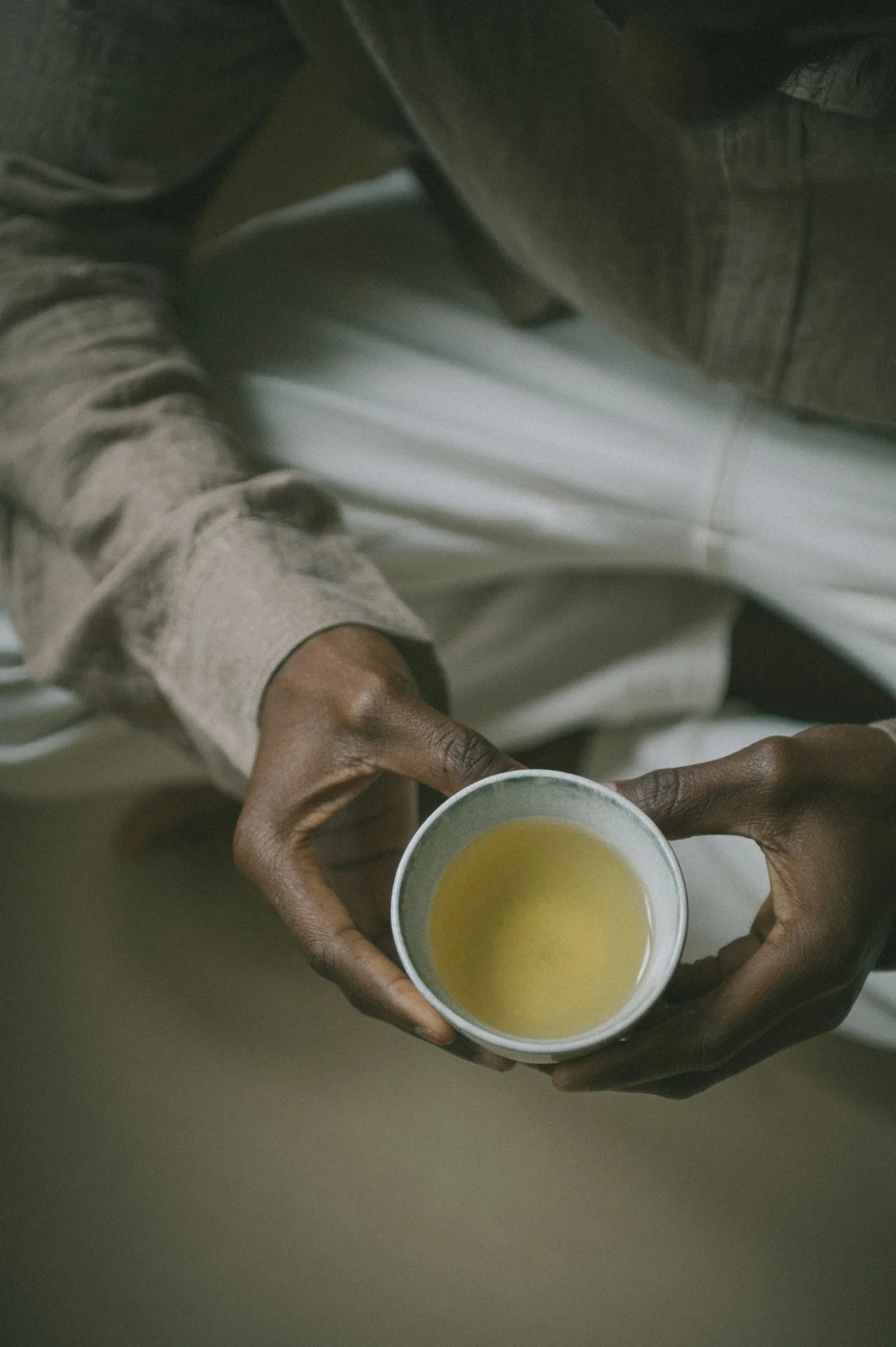 Person holding a cup of yellow-colored beverage, seen from above.