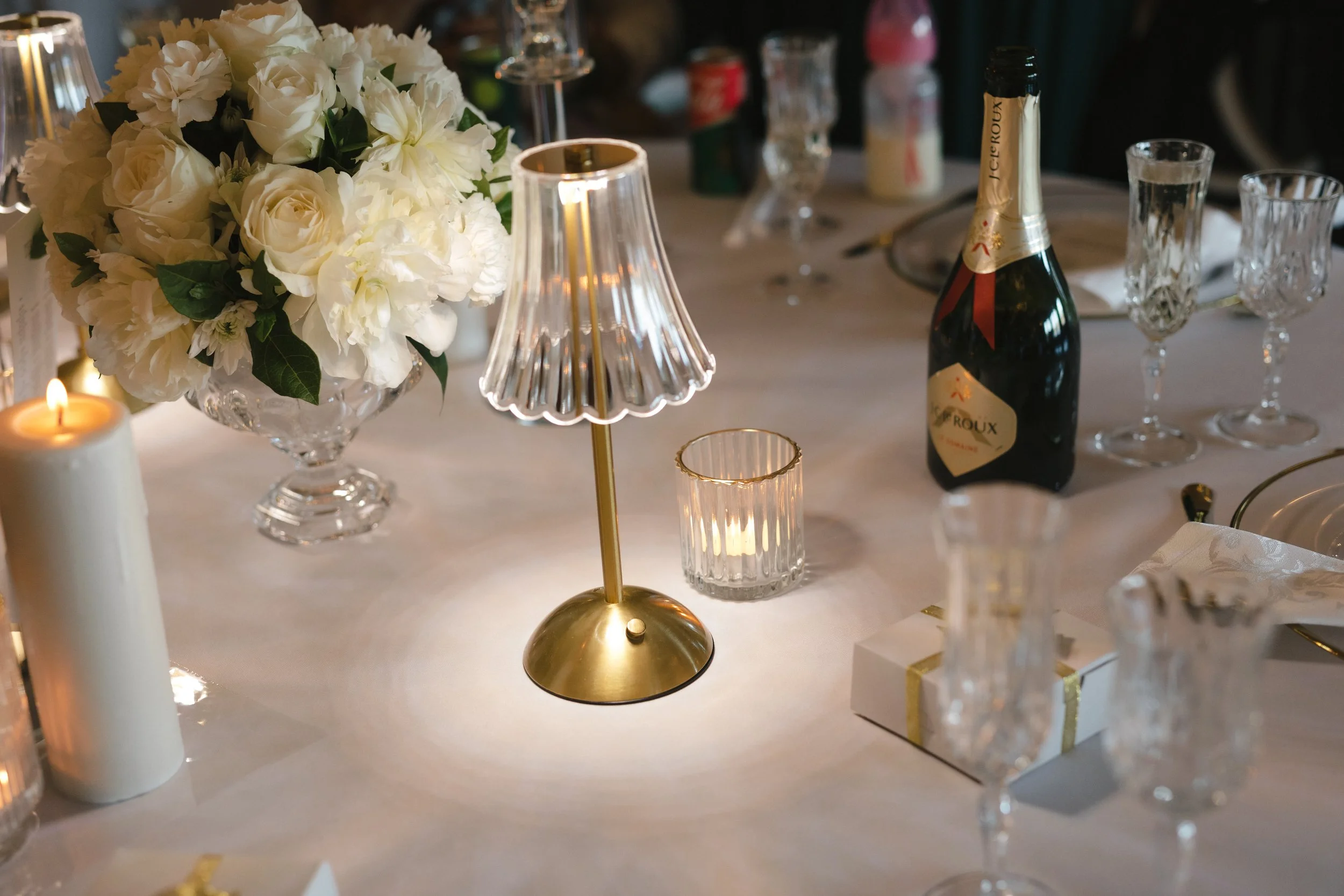 A table set for a celebration with a white floral centerpiece. Gqeberha wedding photographer at Royalston Lakehouse, decor by The Hire Warehouse Flowers - Floral Creations