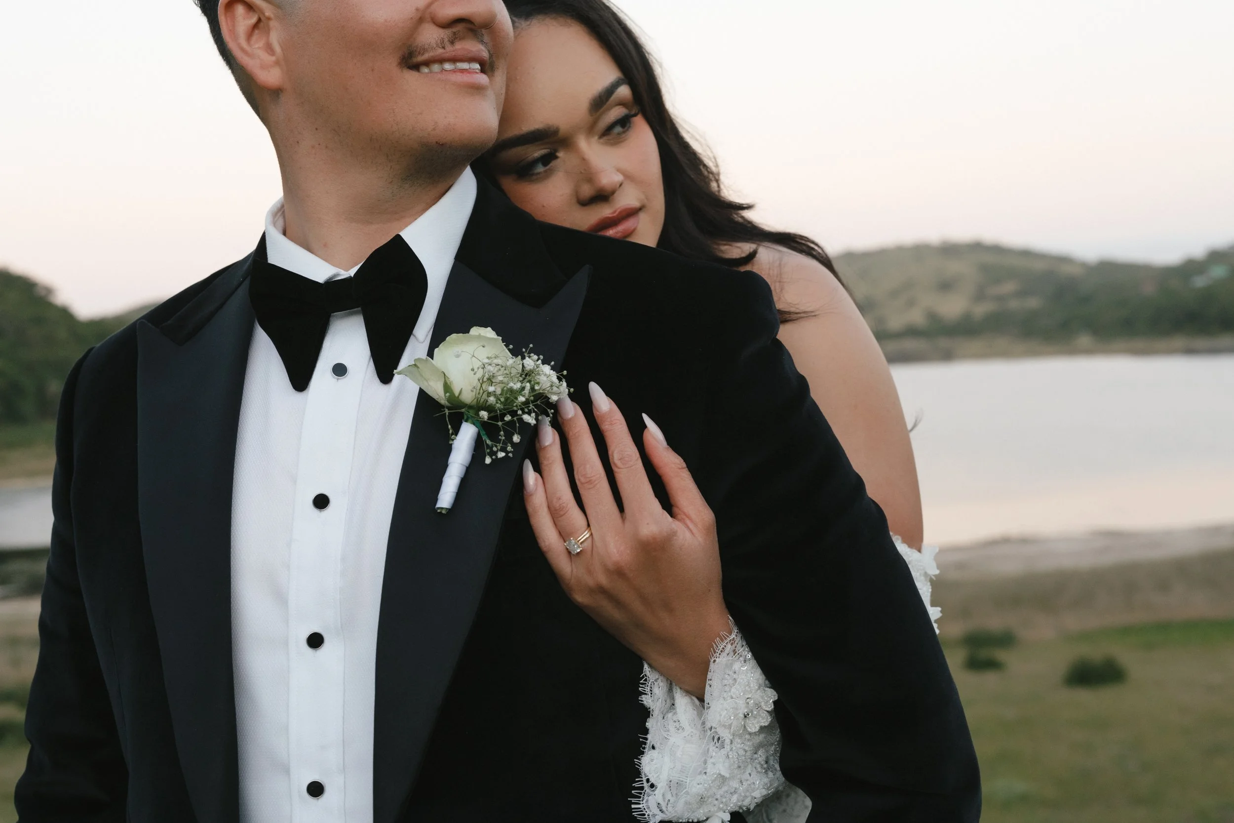A couple dressed in wedding attire embracing outdoors near water and greenery during sunset. Gqeberha wedding photographer at Royalston Lakehouse.