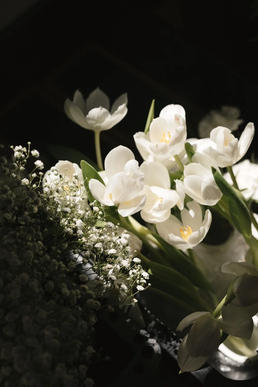 White flowers, including lilies and baby's breath, arranged with soft lighting against a dark background. Gqeberha wedding photographer.