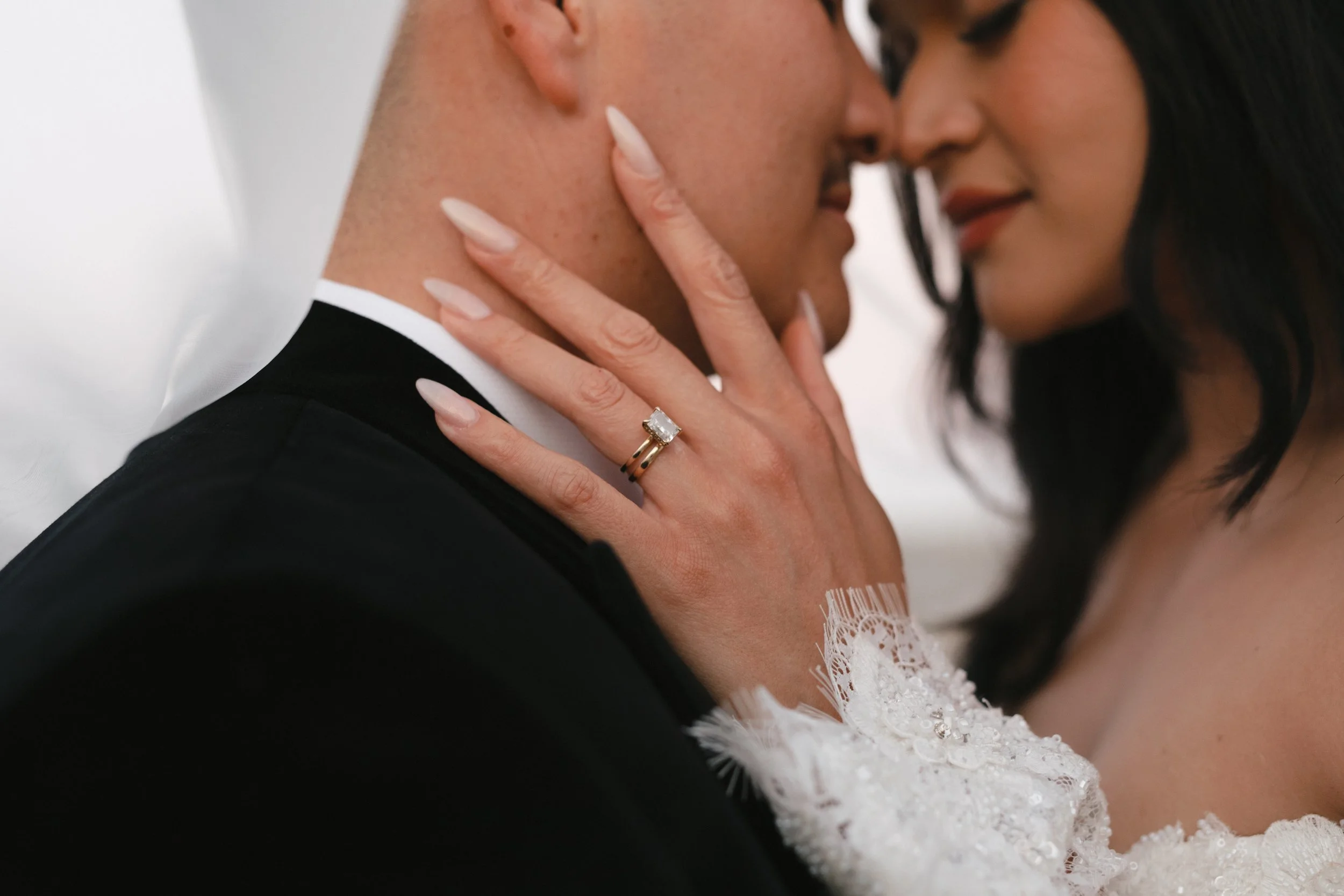 Close-up of a bride and groom sharing an intimate moment, with the bride touching the groom's face and wearing a wedding ring. Gqeberha wedding photographer at Royalston Lakehouse, decor by The Hire Warehouse Flowers - Floral Creations