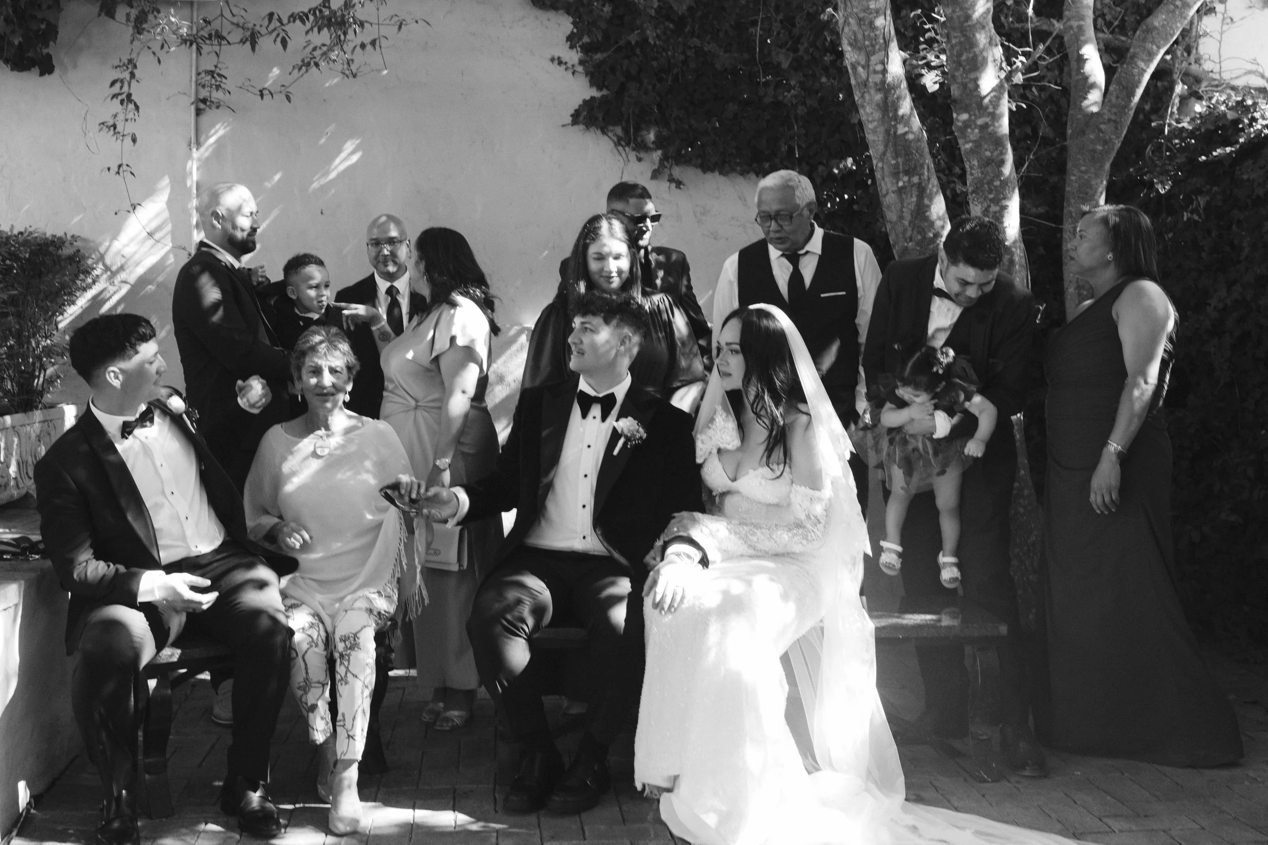 A black and white photo of a group of people gathered outdoors, including children and adults, at what appears to be a wedding. Dusty Pink Events, Gqeberha wedding photographer at Royalston Lakehouse.