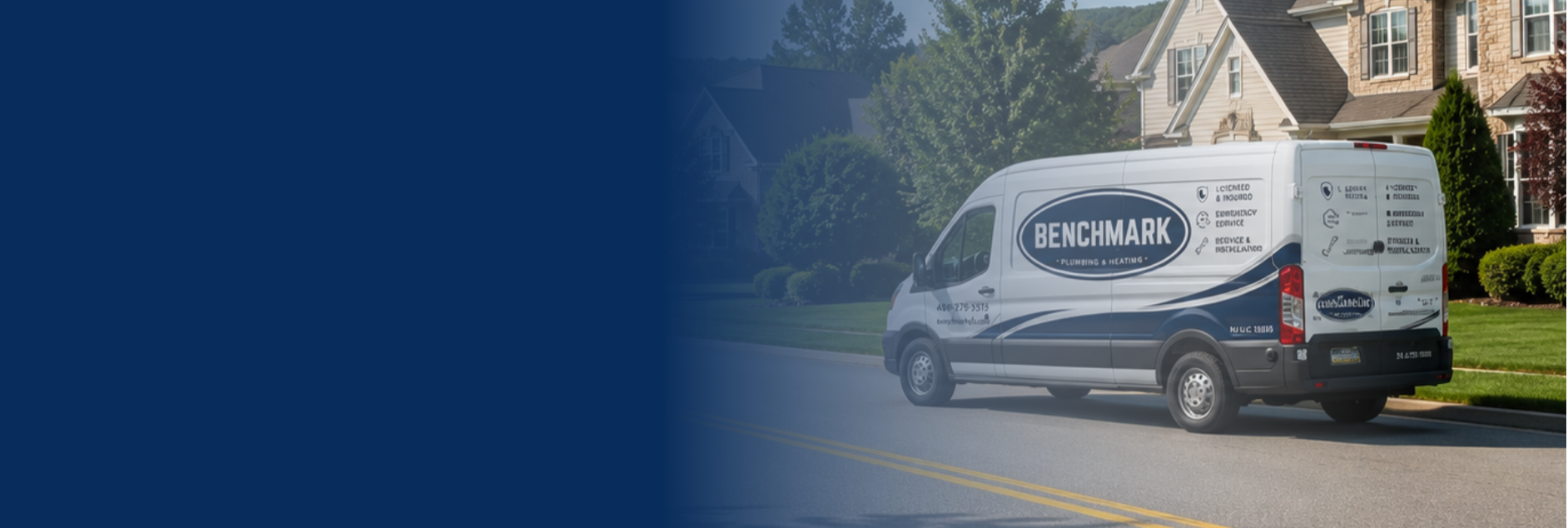 A white service van parked on a suburban street in front of a house with a well-maintained lawn and trees. The van has the logo and contact information for Benchmark Plumbing & Heating, with various service icons and text on the side.