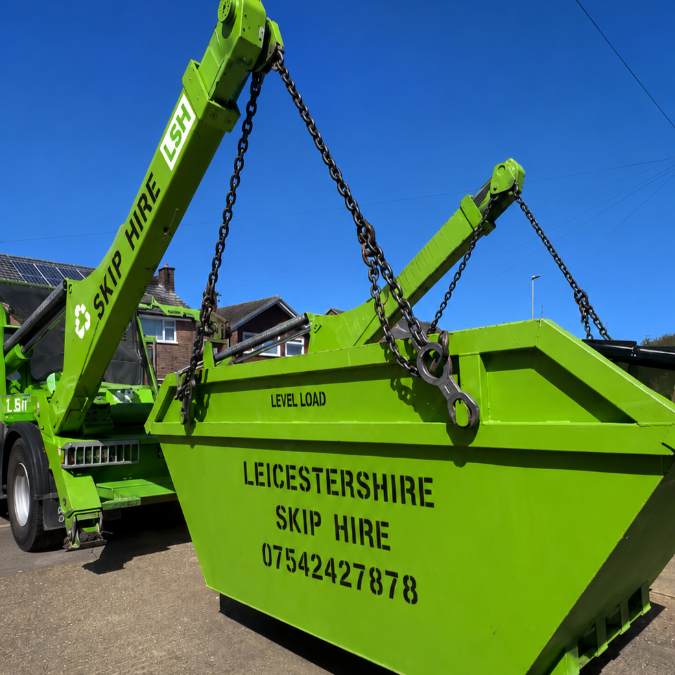 Large green skip loader with a skip labeled "Leicestershire Skip Hire" and phone number, parked on a residential street under a clear blue sky.