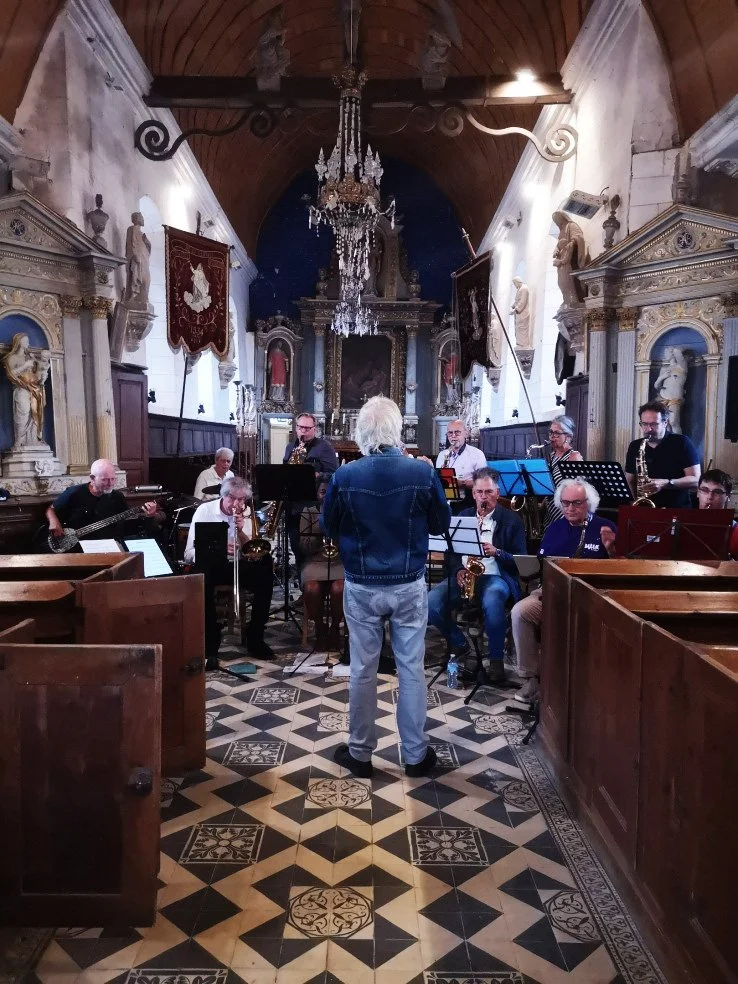 Een jazzband speelt in een kerk met barokke architectuur, met baronnen en een chandelier aan het plafond.