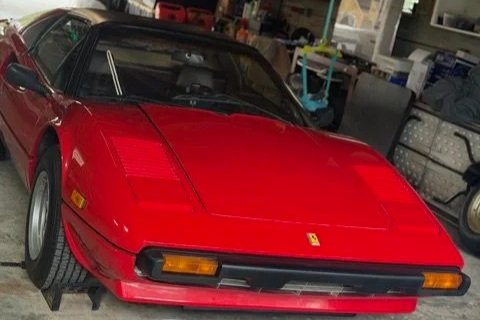 Red Ferrari sports car in a garage prepped for work.