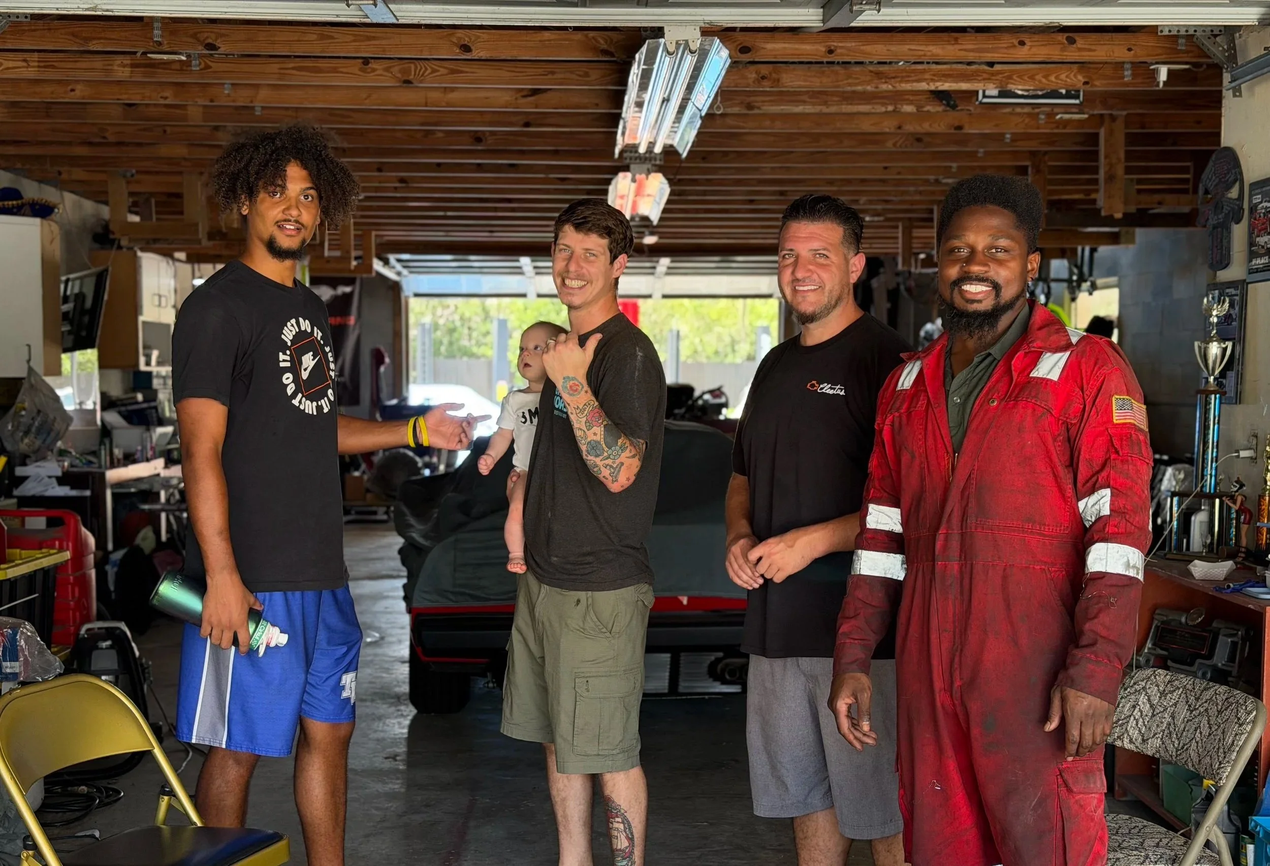 Four men standing together inside a garage, with tools and equipment nearby.