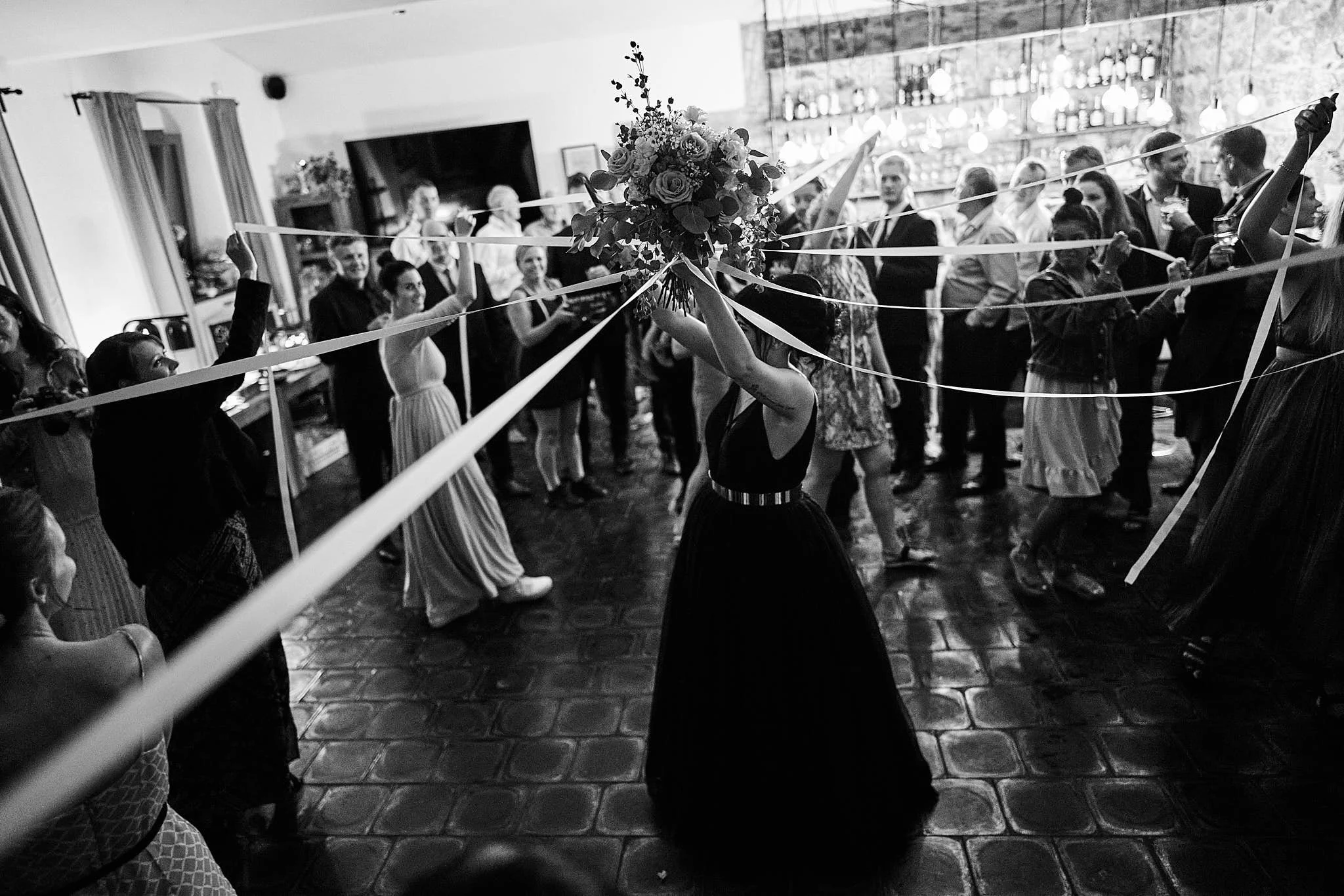 People dancing at a wedding reception, with a floral centerpiece and ribbon decorations.