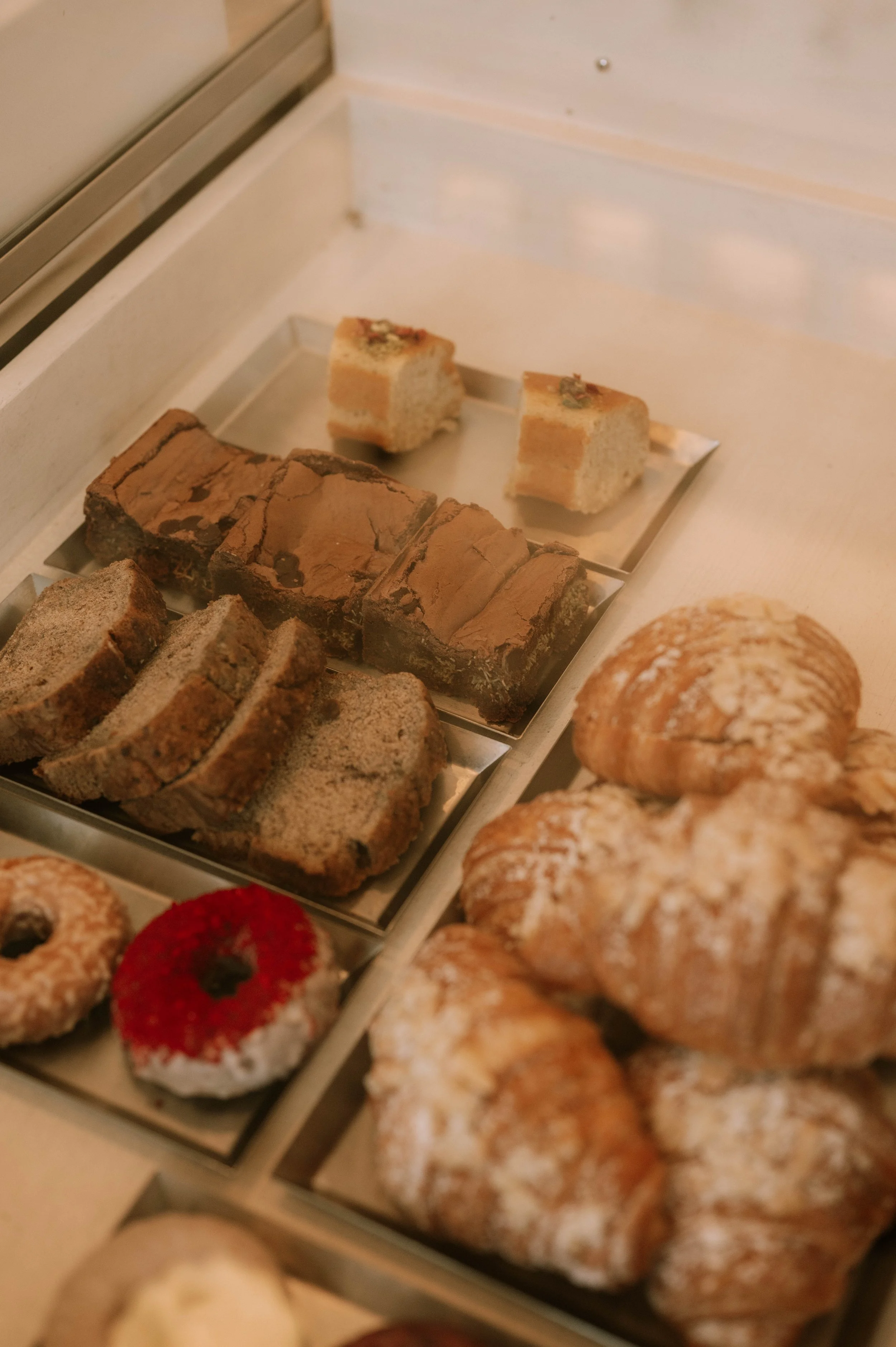 Tray of assorted bakery items including brownies, cakes, donuts, and other pastries.
