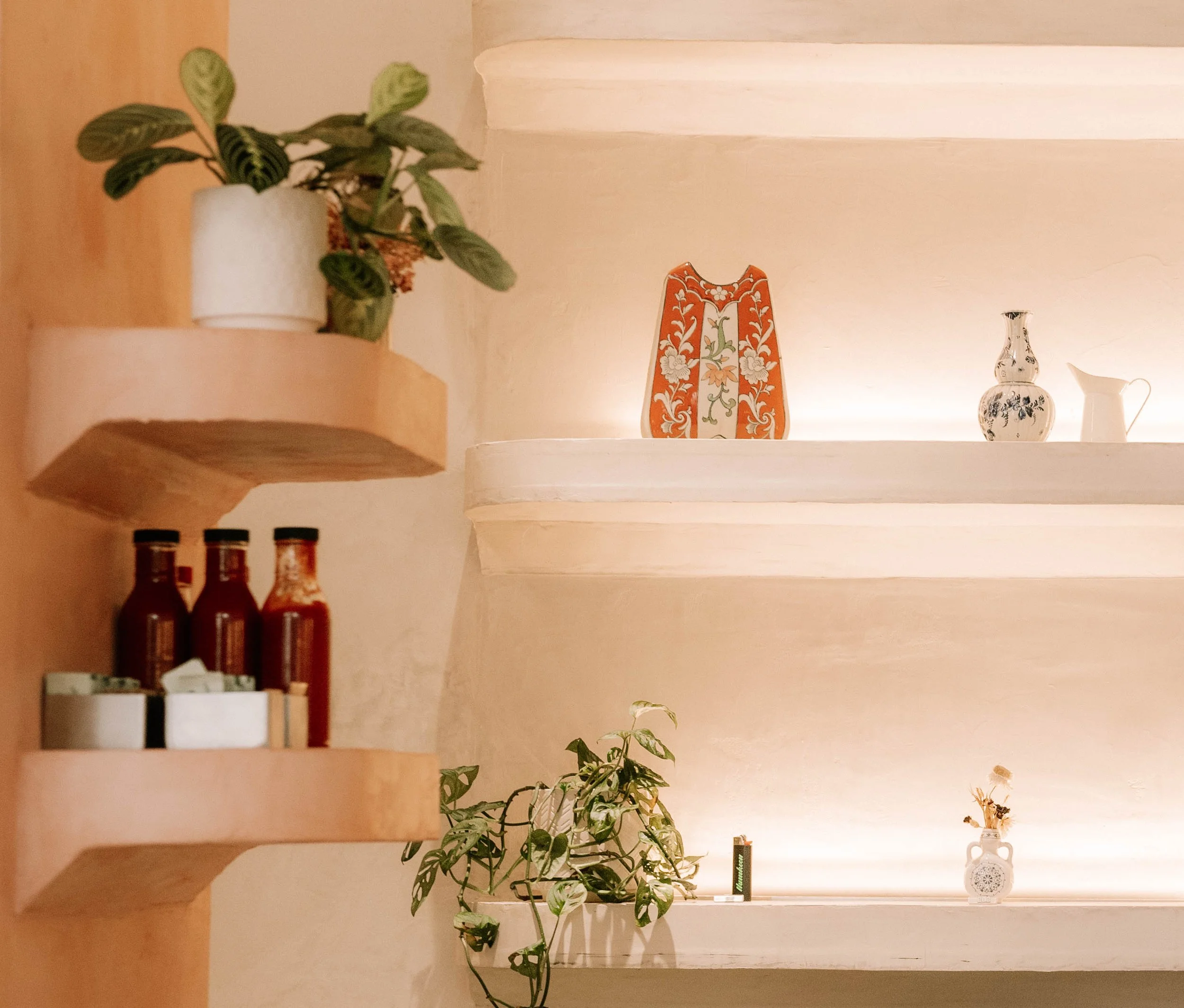 Decorative shelf with potted plants and vintage vases in a cozy home interior.