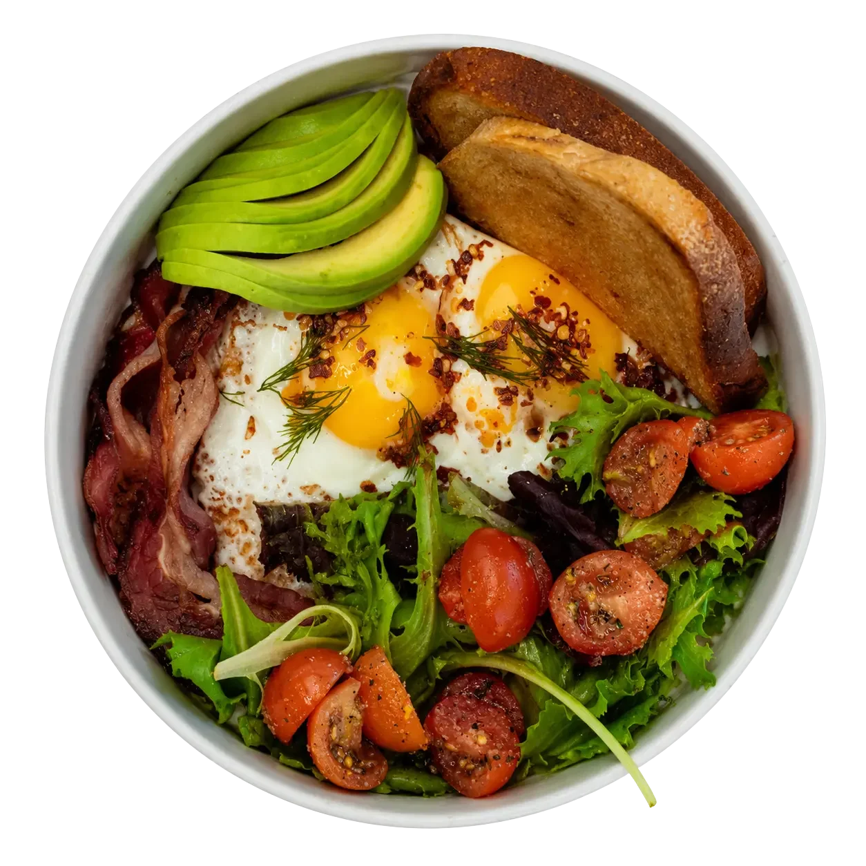 Bowl with avocado slices, crispy bacon, fried eggs garnished with herbs and chili flakes, toasted bread slices, cherry tomatoes, and mixed greens.