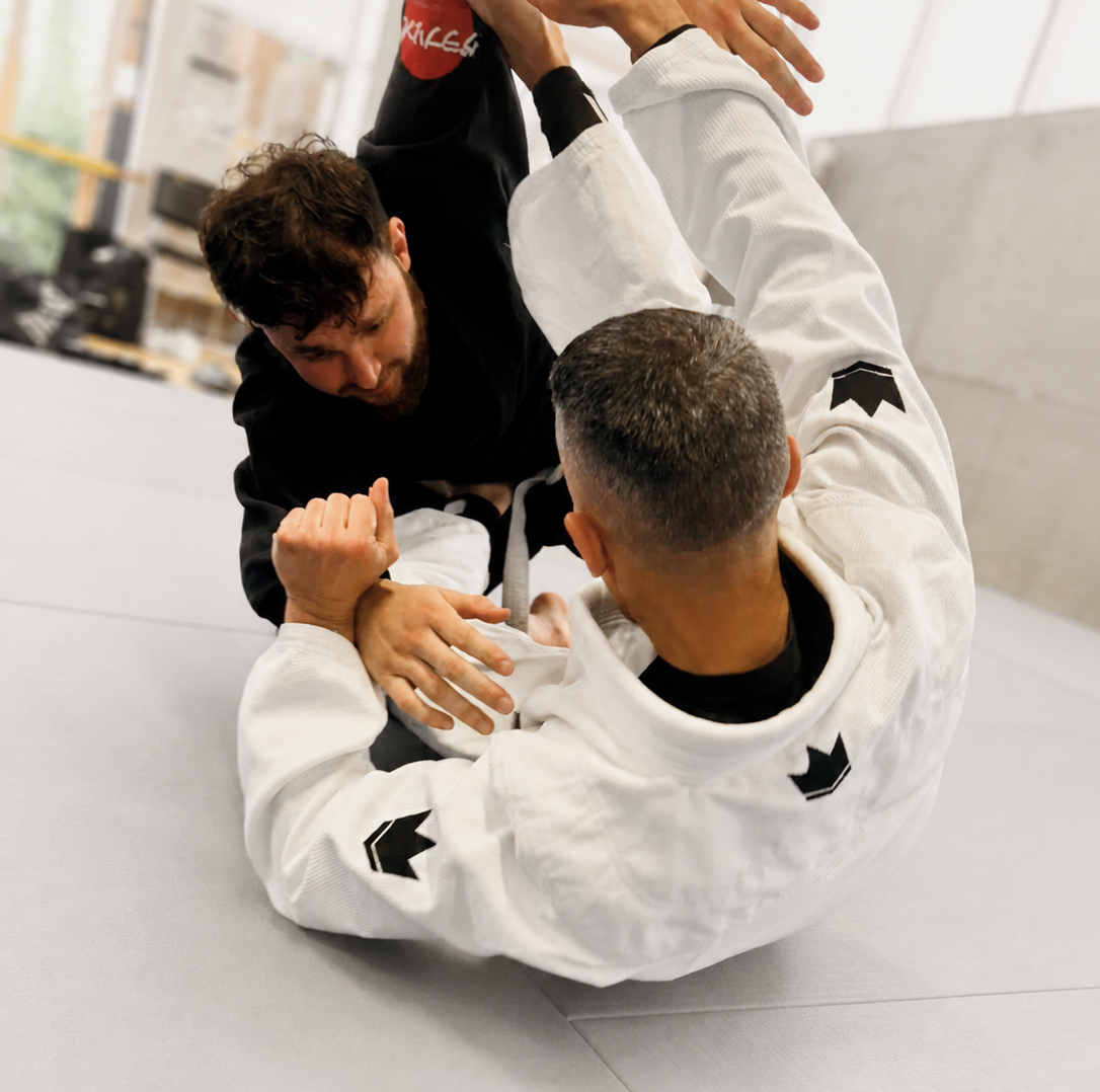 Deux personnes pratiquant le jiu-jitsu brésilien s'entraînent sur un tapis d'entraînement, l'une en position de monté et l'autre en défense.